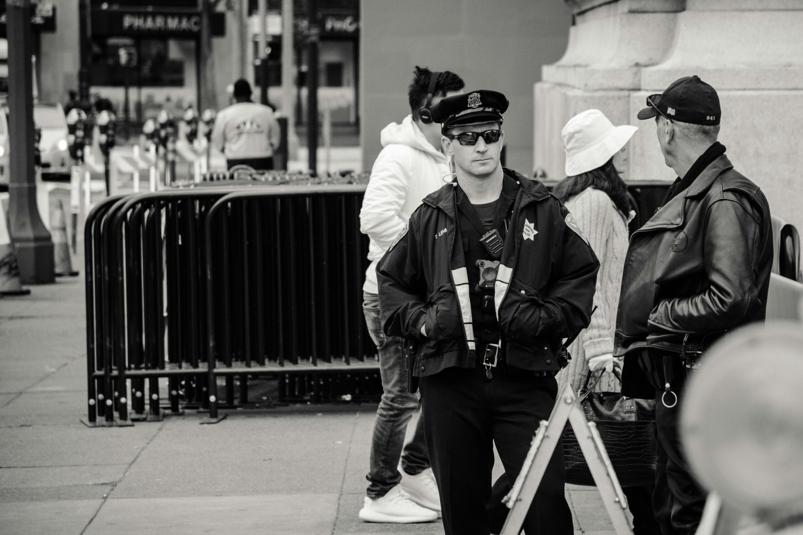 A police officer on patrol in an urban street, engaging in conversation, captured in black and white.